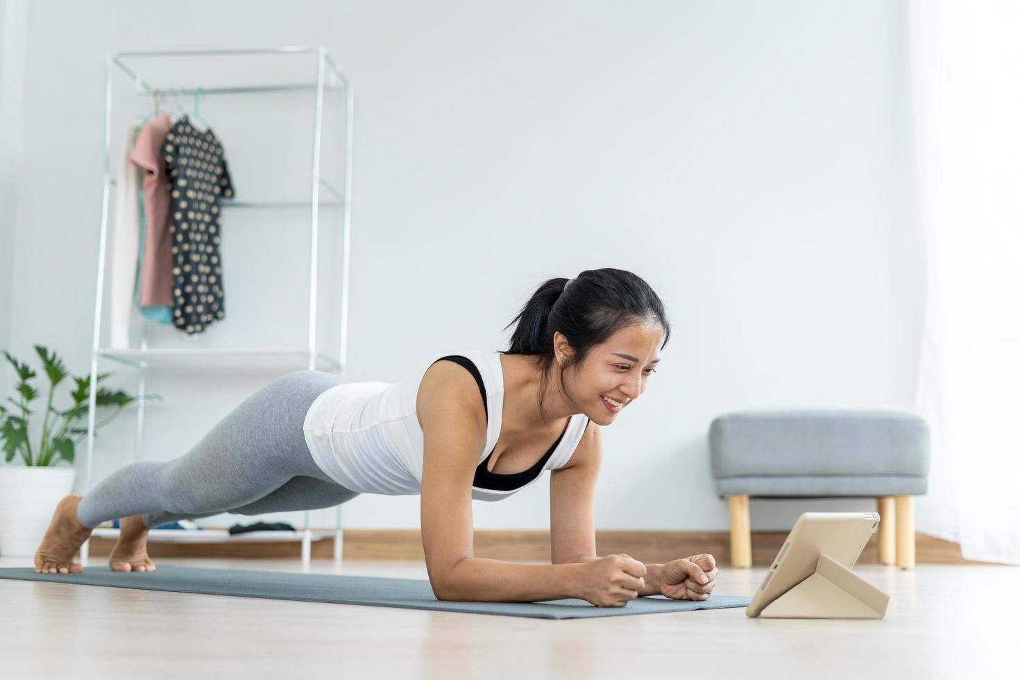 las mujeres jóvenes que usan trajes de fitness están sentadas haciendo yoga en el suelo dentro de la sala de estar en casa relajándose. concepto de estilo de vida saludable. foto