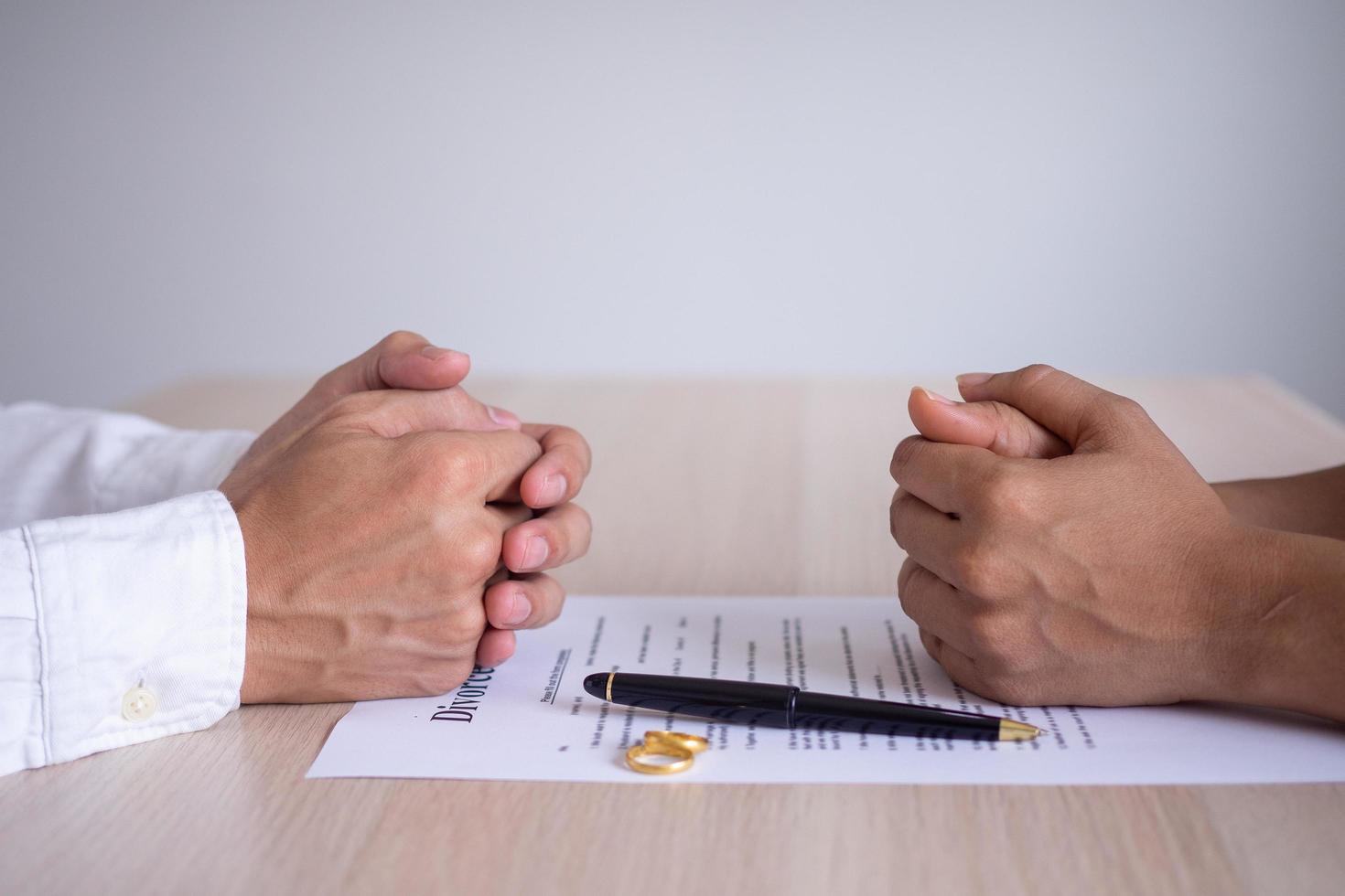 las manos de la esposa y el esposo descansan sobre los documentos de divorcio. presentación de documentos de divorcio o acuerdos prematrimoniales preparados por un abogado. el anillo de bodas representa el pacto de los amantes. foto