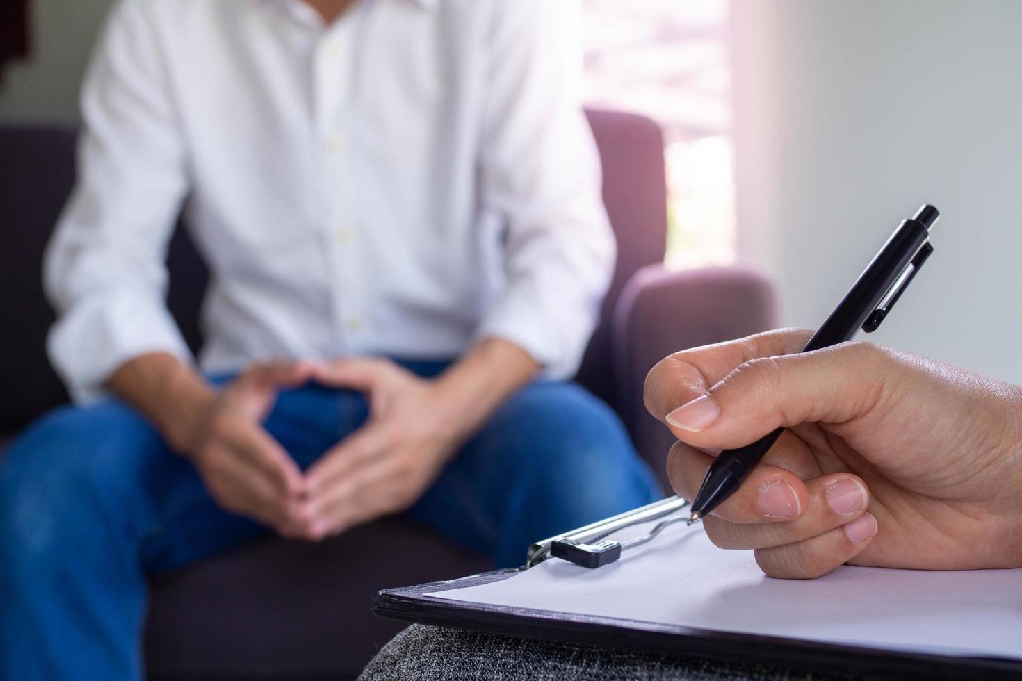 The psychologist talks to the patient and takes notes on the treatment. The patient is addicted to drugs, is stressed and frustrated with life problems. photo