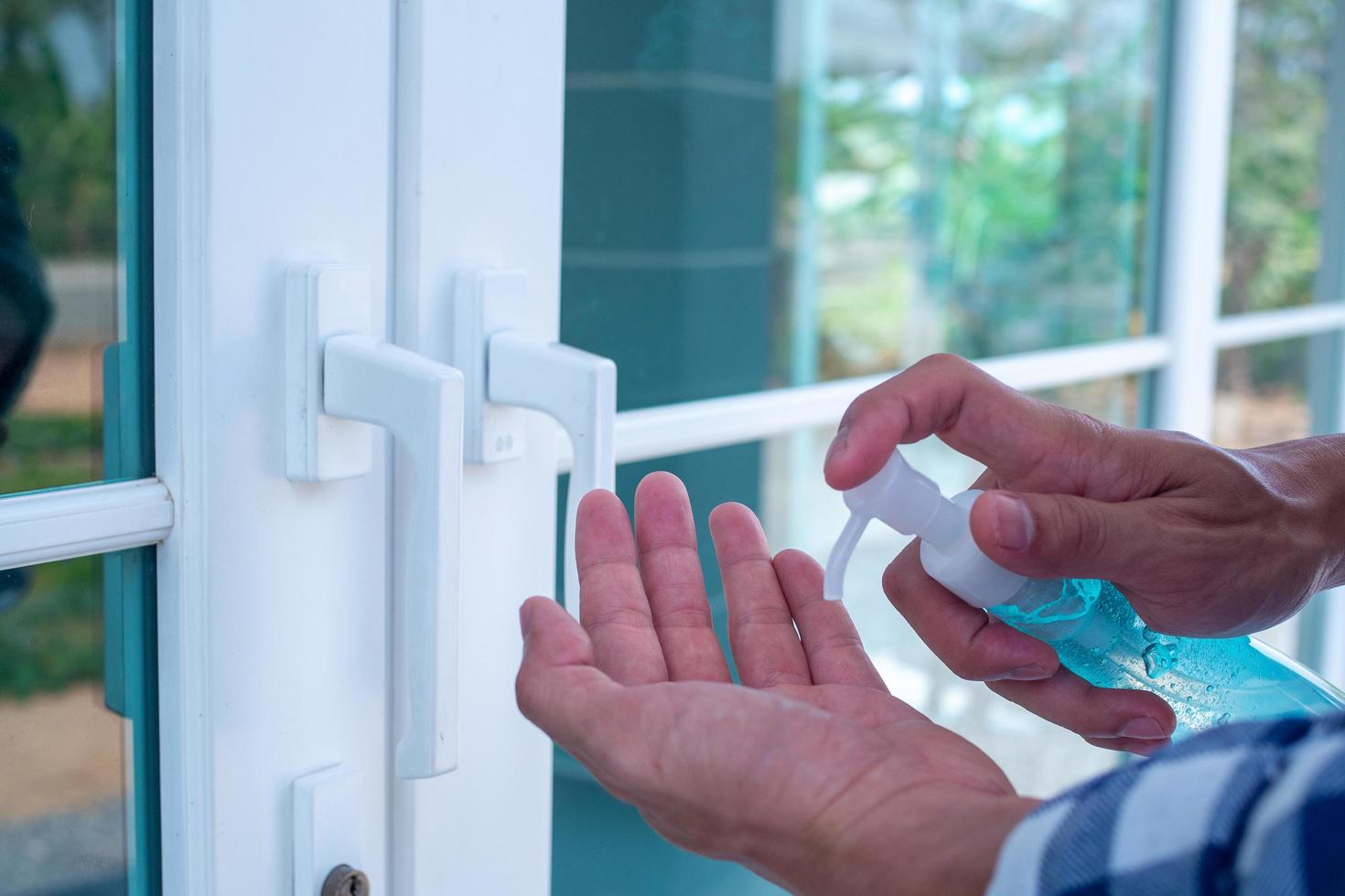 la mano del hombre presionando el gel para lavarse las manos y matar los gérmenes antes de entrar y salir o atrapar puertas. concepto de limpieza e higiene. prevenir covid-19 foto