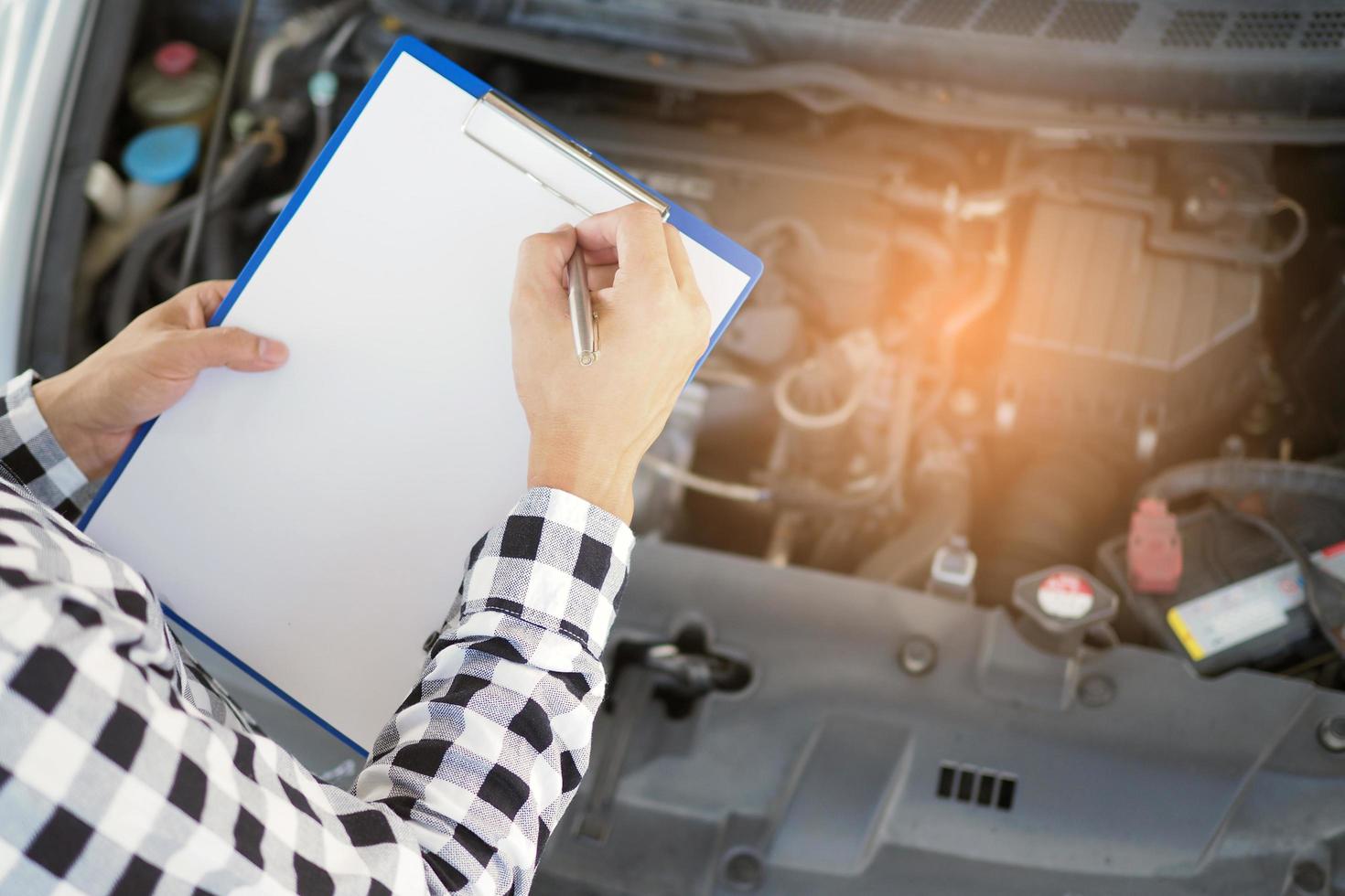 The car mechanic working in the car garage is checking the engine. photo