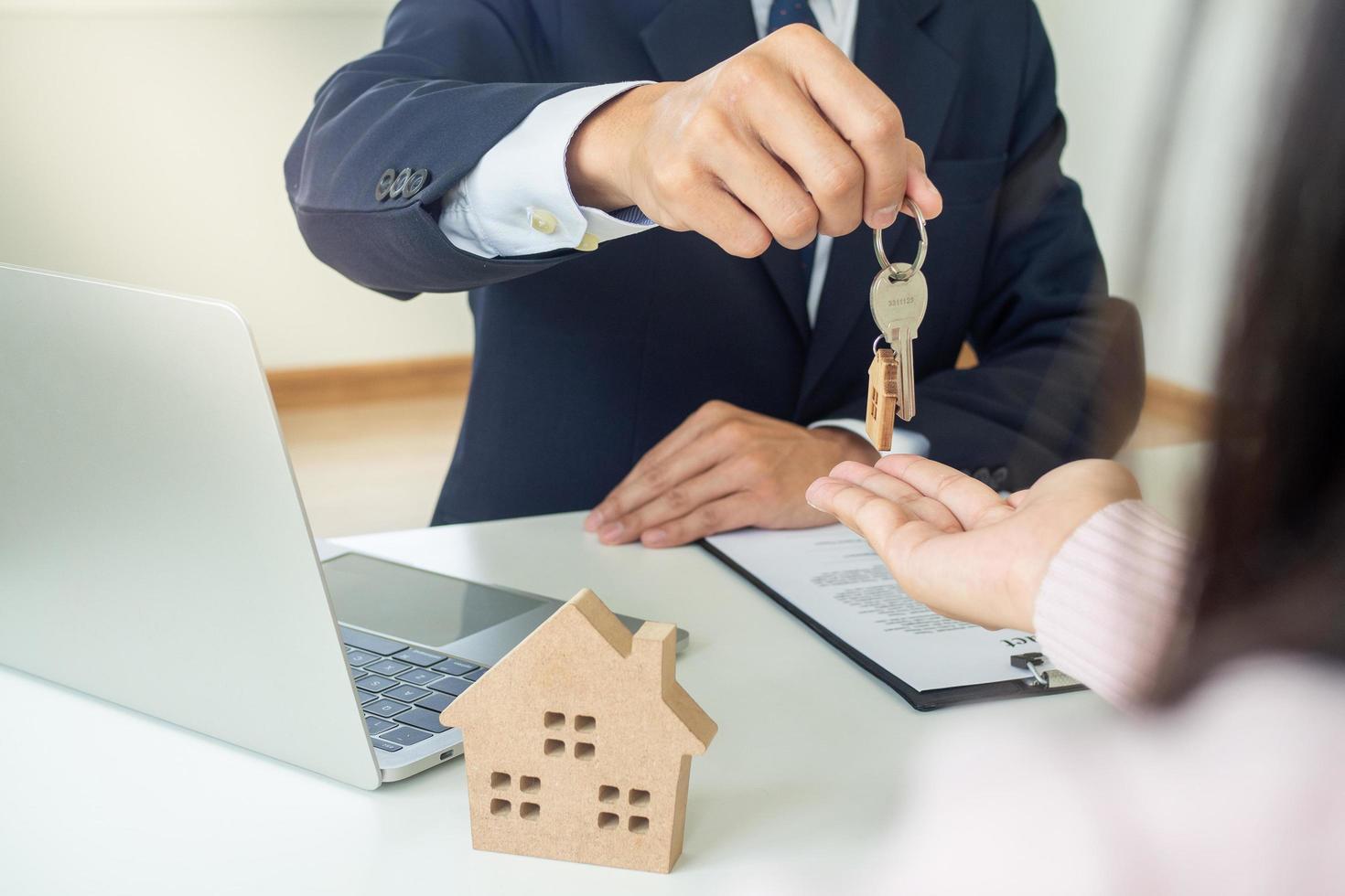 The real estate agent holds the keys house sending the customers' hands after entering into a contract to buy insurance or to recover real estate or real estate. photo