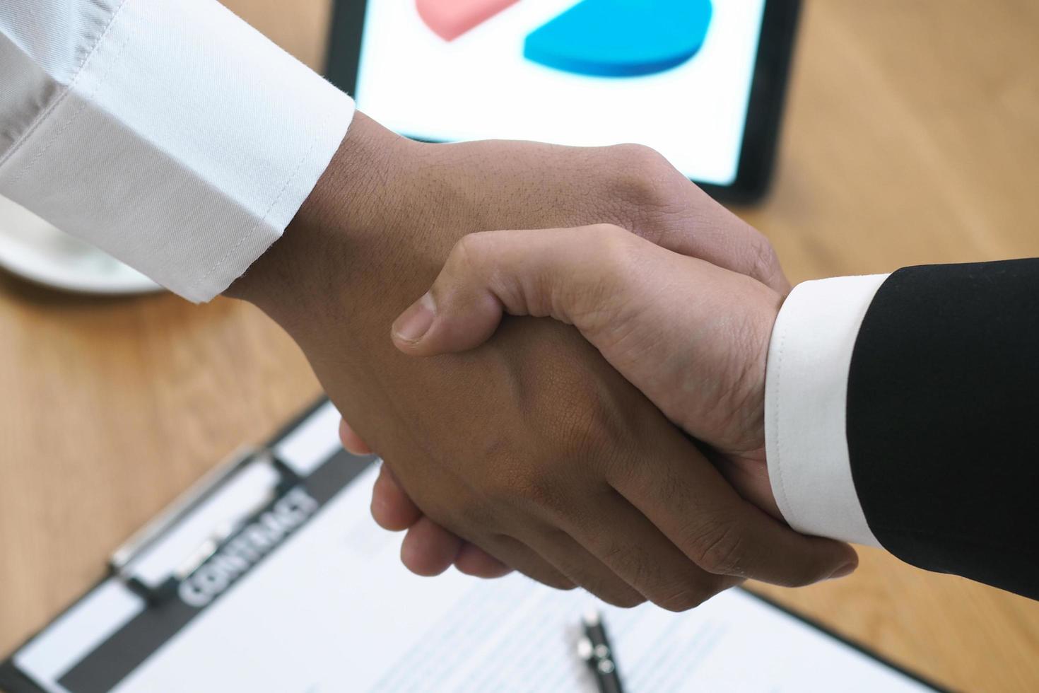 dos hombres de negocios se unen para firmar un contrato después de negociar un acuerdo de inversión y ganancias. foto