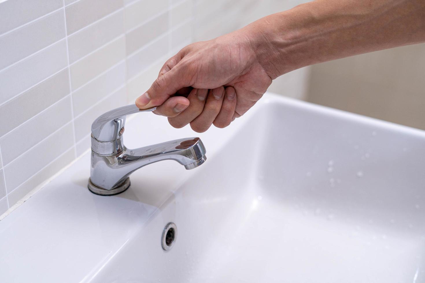 The faucet in the bathroom with running water. Man keeps turning off the water to save water energy and protect the environment. save water concept photo