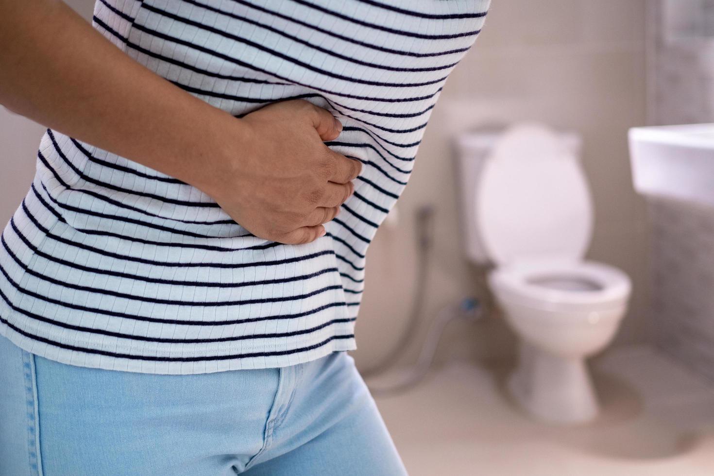 Women are standing in front of the bathroom door using their hands to hold the abdomen with severe abdominal pain or diarrhea. The concept of stomach cramps, diarrhea photo