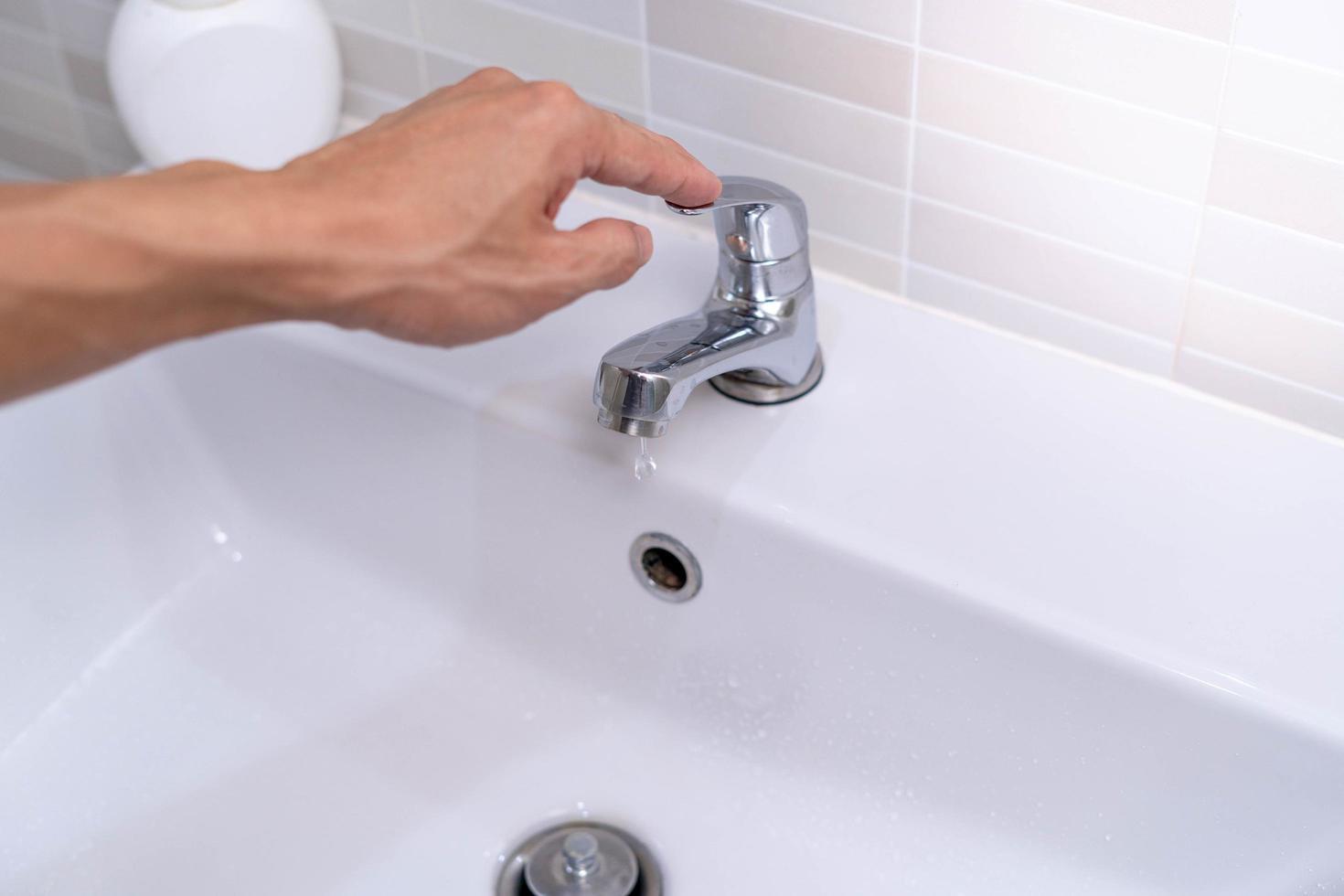 The faucet in the bathroom with running water. Man keeps turning off the water to save water energy and protect the environment. save water concept photo