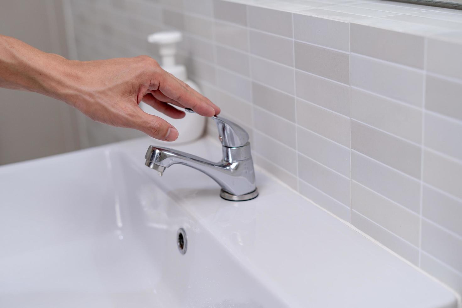 The faucet in the bathroom with running water. Man keeps turning off the water to save water energy and protect the environment. save water concept photo