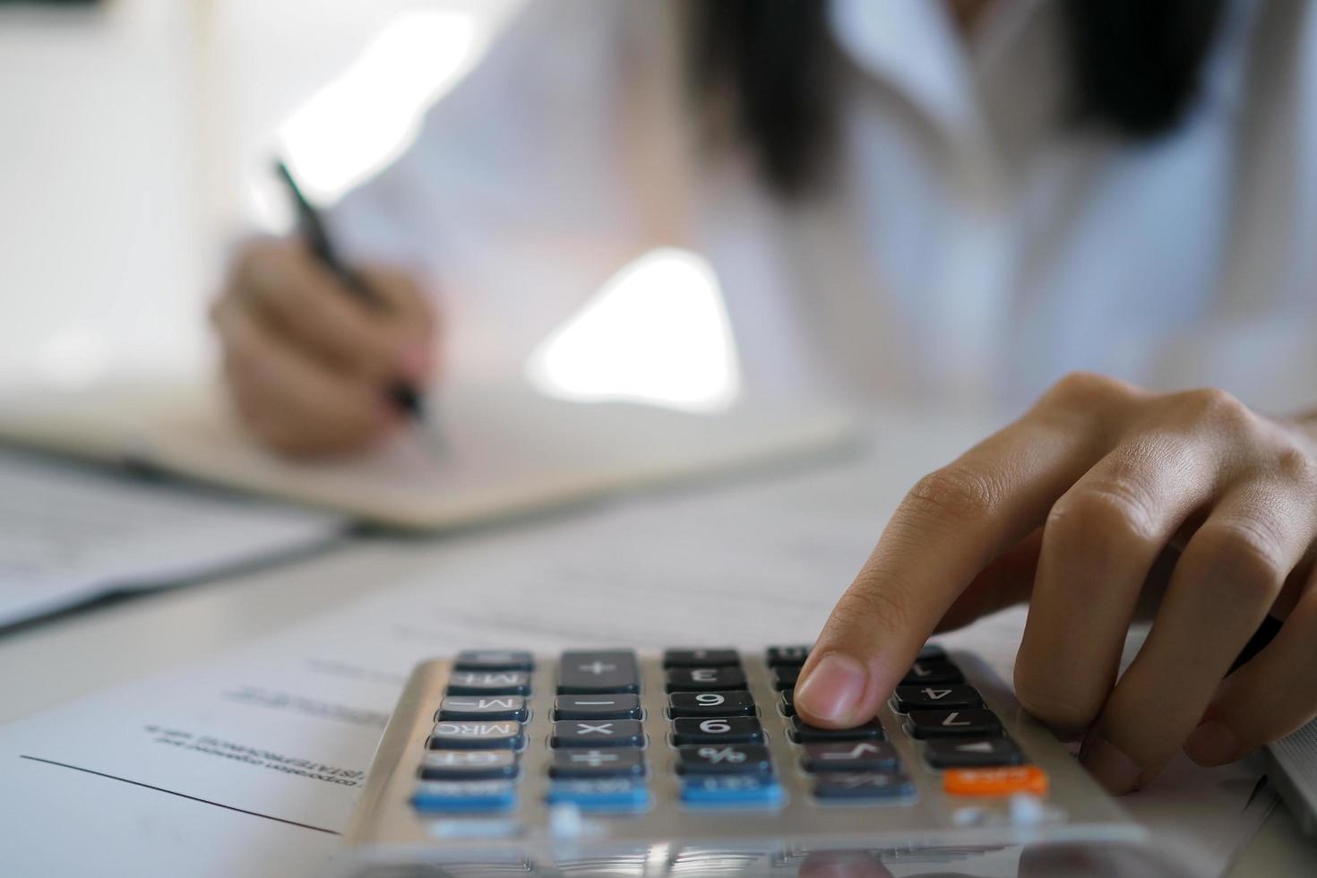 Asian businessmen work with calculators to calculate account information. In the office, work desks with documents and computers photo