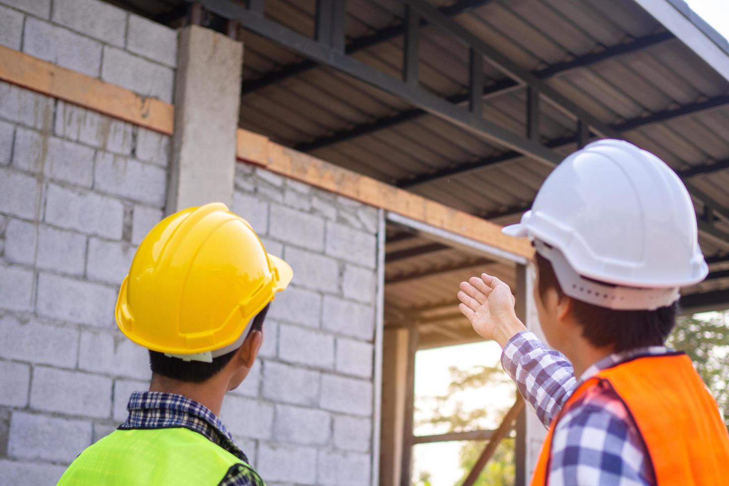 The inspector is checking with the checklist and pointing out the new building with the structure and materials used to the customer or client. Inspection and engineering concept photo