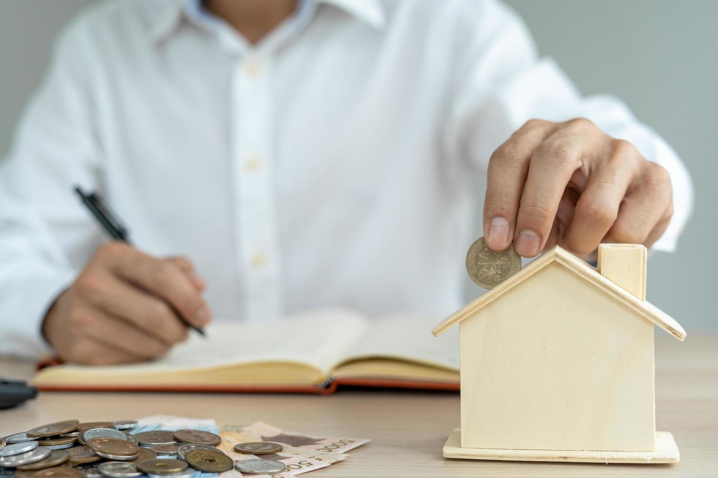 The man is putting two coins into his savings each month. A pig piggy bank holder and is show to the front as a symbol of savings. monthly savings concept. photo