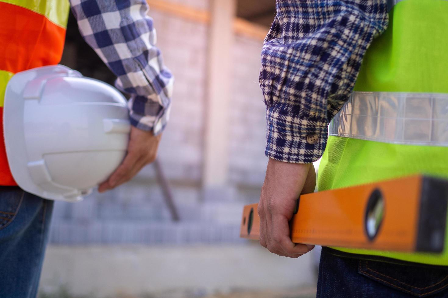 Professional engineers and builders in work clothes with tools and holding white helmets while standing outside the construction site. photo