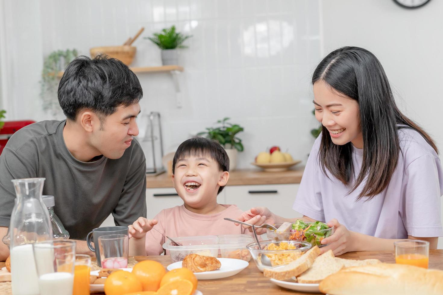 actividades juntos durante las vacaciones. padres e hijos están comiendo juntos durante las vacaciones. el niño se burla de su padre dándole pan y verduras. foto