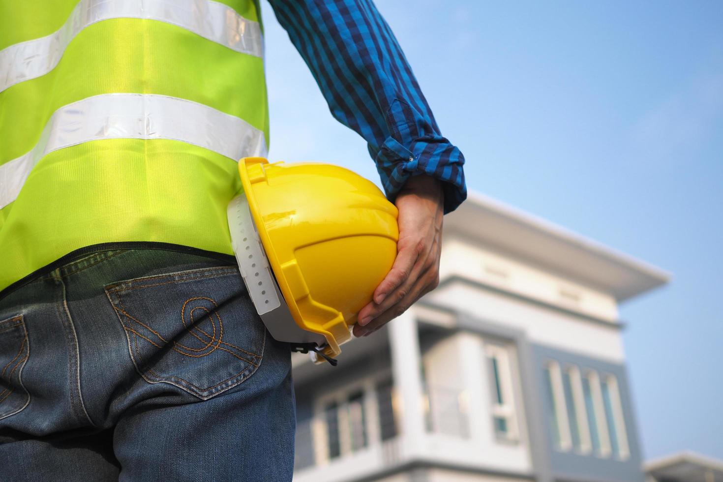 Construction staff holding a hard hat with an external house built