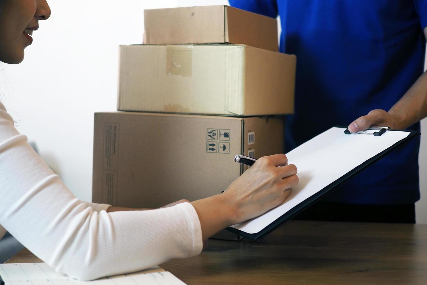 The shopper girl signs on the clipboard to receive the package box from the delivery man. Fast delivery service photo