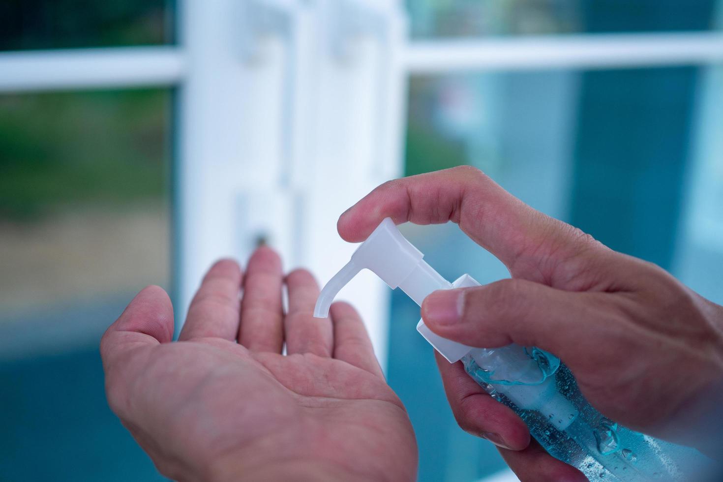 manos humanas que usan gel de alcohol para limpiar y lavar gérmenes, bacterias y virus antes de entrar a la casa. conceptos de atención de la salud. prevenir covid-19 foto