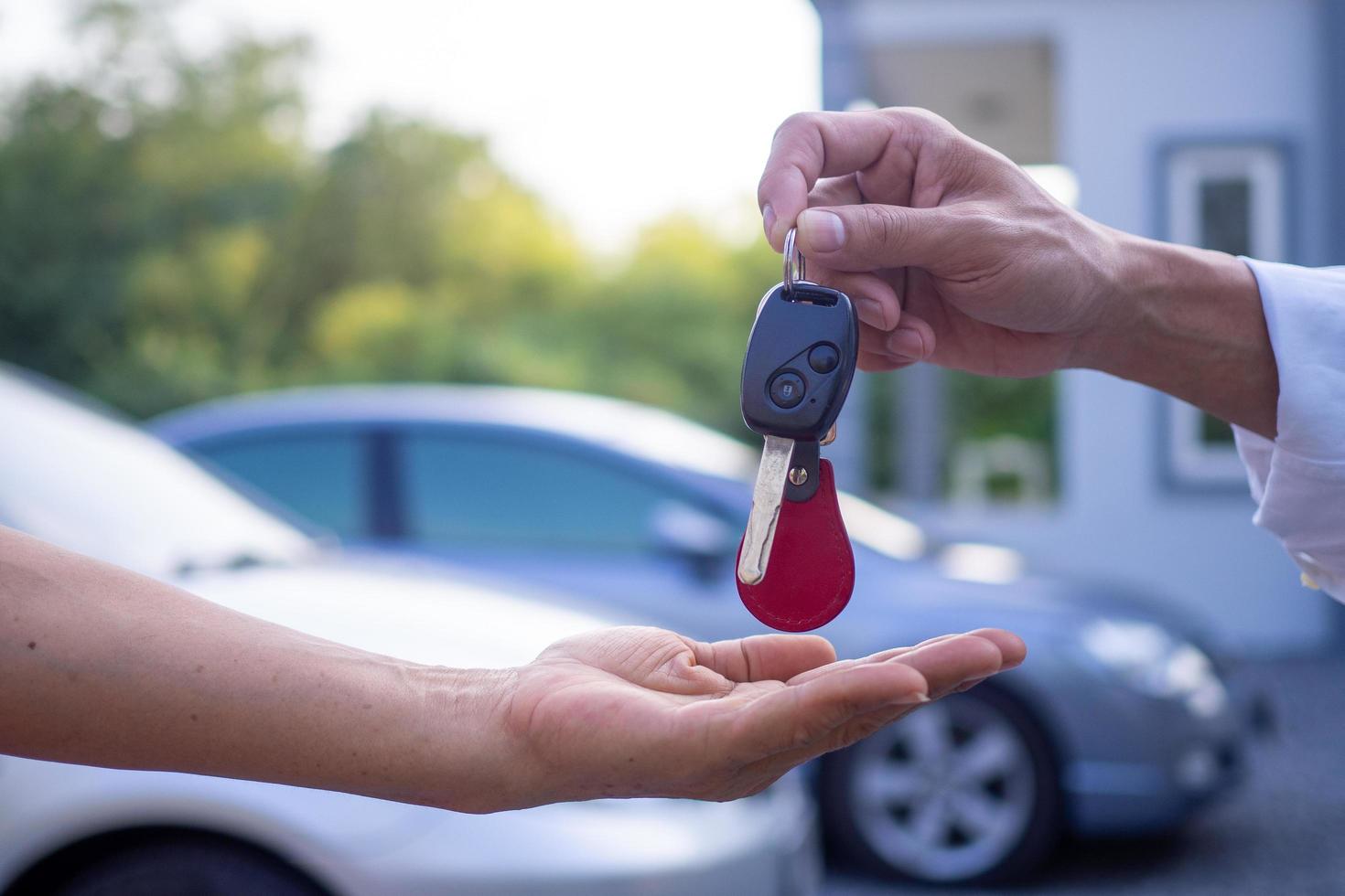 el vendedor masculino envía las llaves y el auto al cliente en casa. concepto de venta de autos y alquiler de autos con buen servicio foto