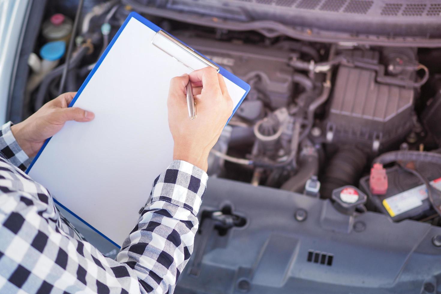 The mechanic is checking the condition. Write down the maintenance items on the clipboard. photo