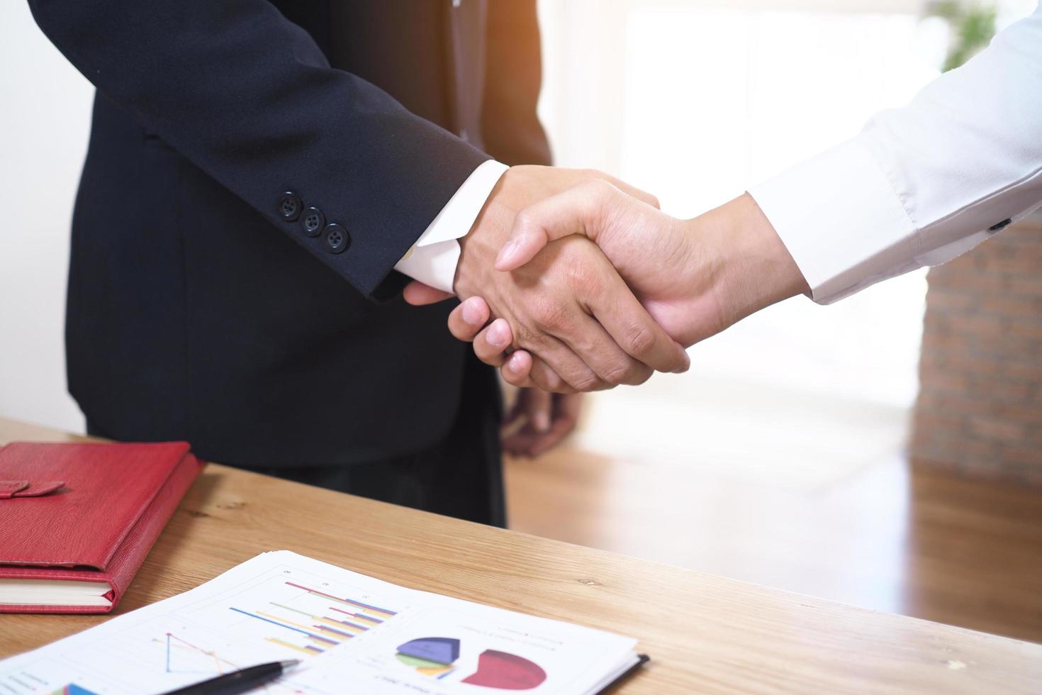 Businessmen join hands to invest and share profits in real estate projects. On the table, there are documents and historical performance data. photo