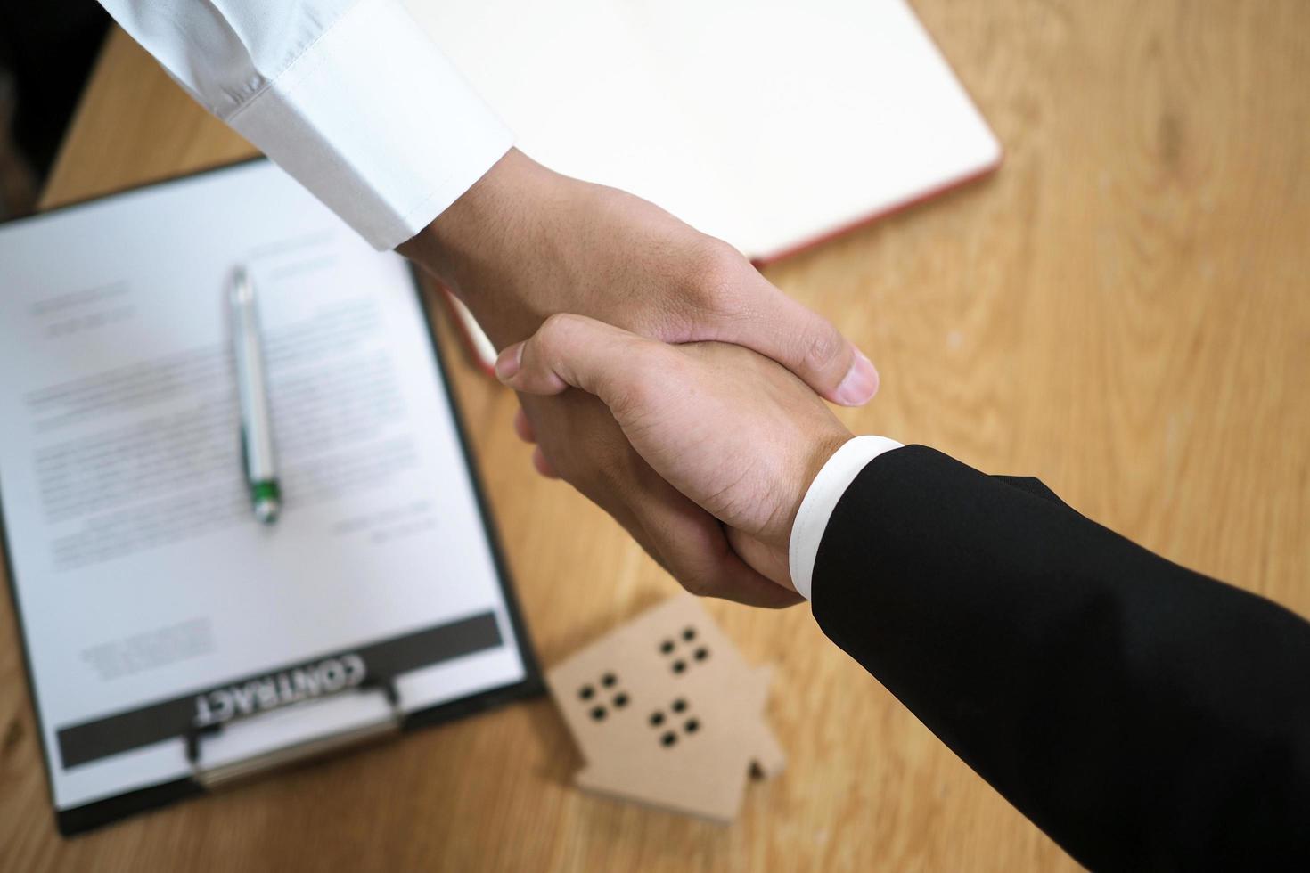 Businessmen handshake to invest and share profits in building and residential projects. Have a contract document that has legal effect photo