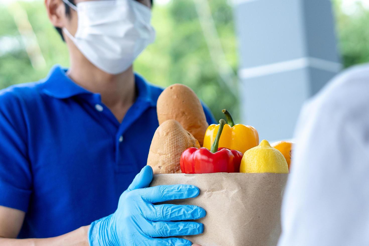 Food delivery staff wearing masks during the Covid-19 outbreak. Postman carry food bags to customers in front of the house. Order online and fast delivery service photo