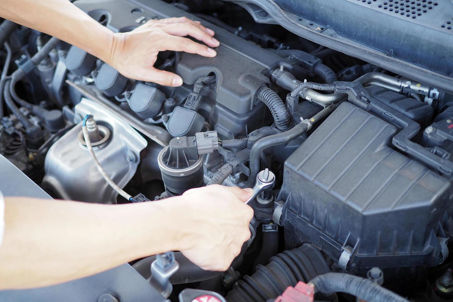 el ingeniero del motor está revisando y reparando el automóvil. servicios de atención fuera del sitio foto