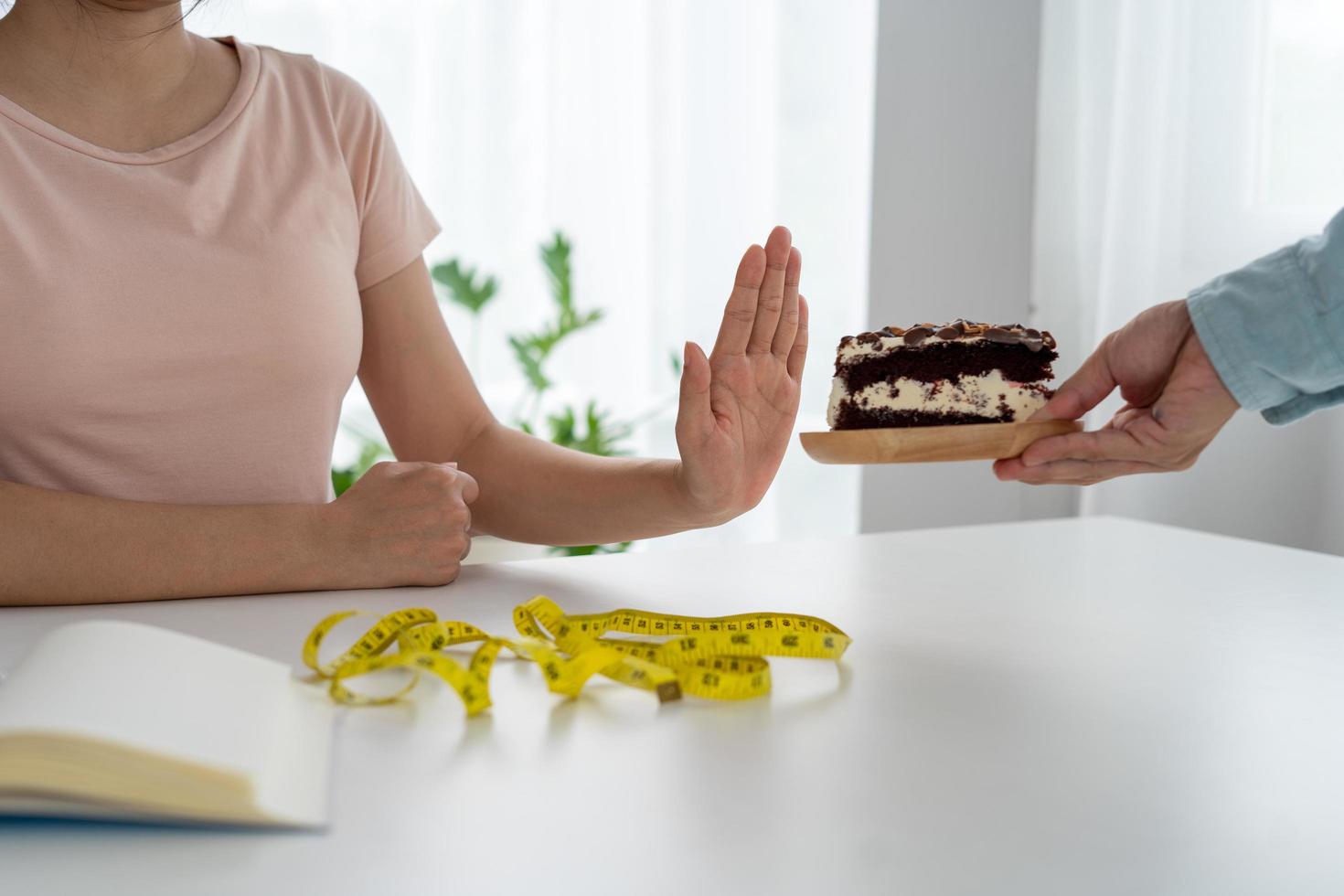 las mujeres flacas se niegan a comer pastel de chocolate. las mujeres no comen grasas trans y azúcar. concepto de dieta foto