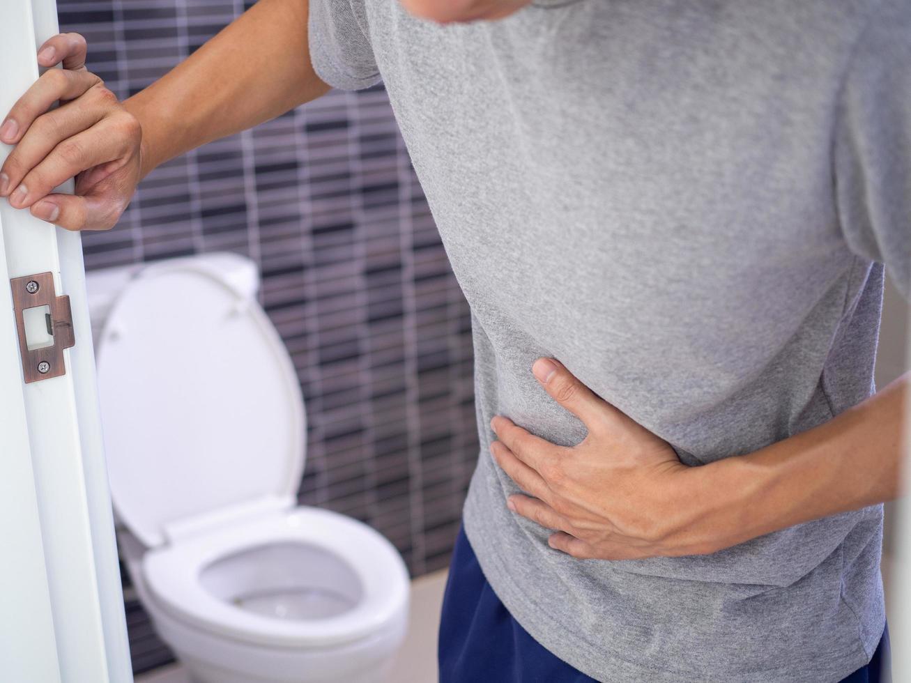 los hombres tienen dolor de estómago y usan sus manos para sostener su estómago en el baño. estreñimiento o cáncer de colon foto