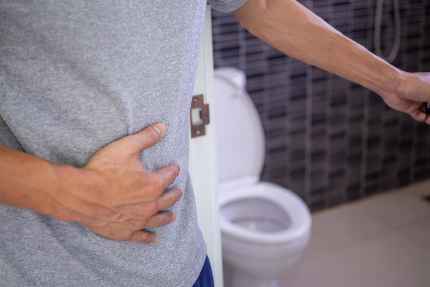 Men have stomachache and use their hands to hold their stomach In the bathroom.  Constipation or colon cancer photo