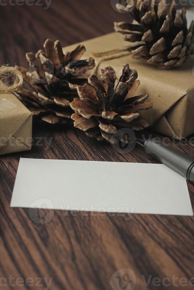 cajas de regalo envueltas en papel reciclado y tarjetas de regalo, cajas de regalo de año nuevo colocadas sobre una mesa de madera, un espacio de copia y una caja de regalo de navidad marrón. foto