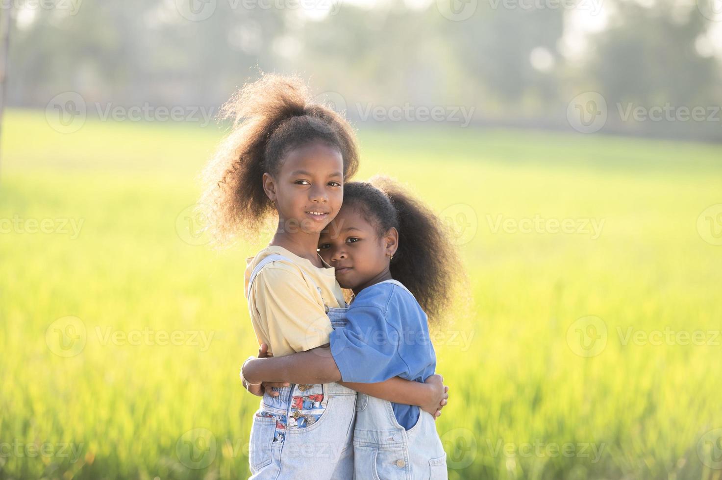 primer plano al aire libre de dos lindas hermanas negras sonriendo al atardecer. foto