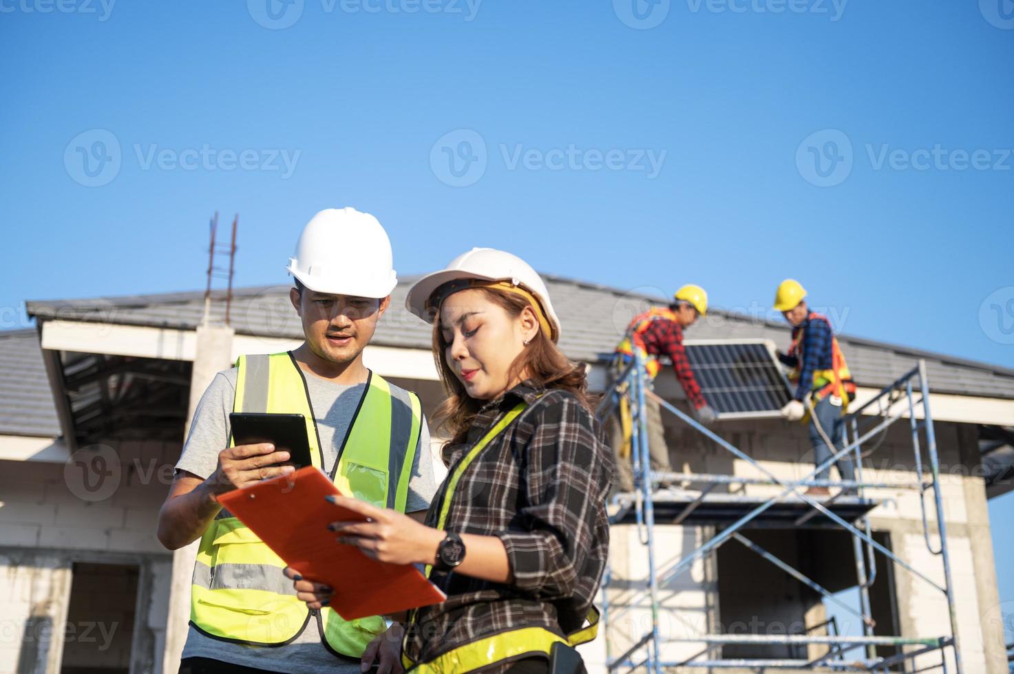 Construction inspector and female architect discuss with chief engineer Asia about installing solar panels on a construction project. Visit the construction site to install solar panels. photo