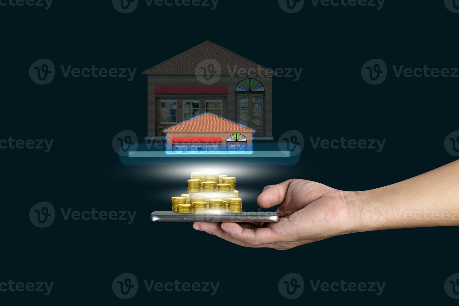 Human hand holding mobile smart phone with piles of golden coins and store isolated on black background photo