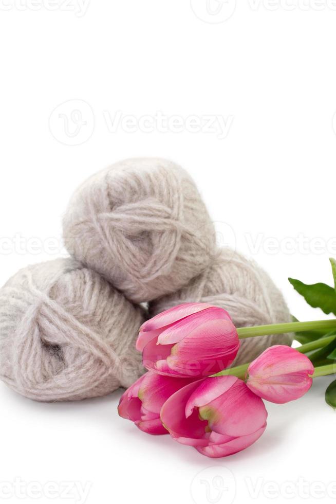 Group of gray wool of yarn and thread with pink tulip on white isolated background. Knitting, hobby, winter. Copy space. Sideview. International women's and mother's day, 8 March, birthday photo