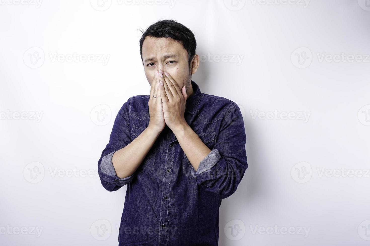 A portrait of an Asian man wearing a blue shirt isolated by white background looks depressed photo