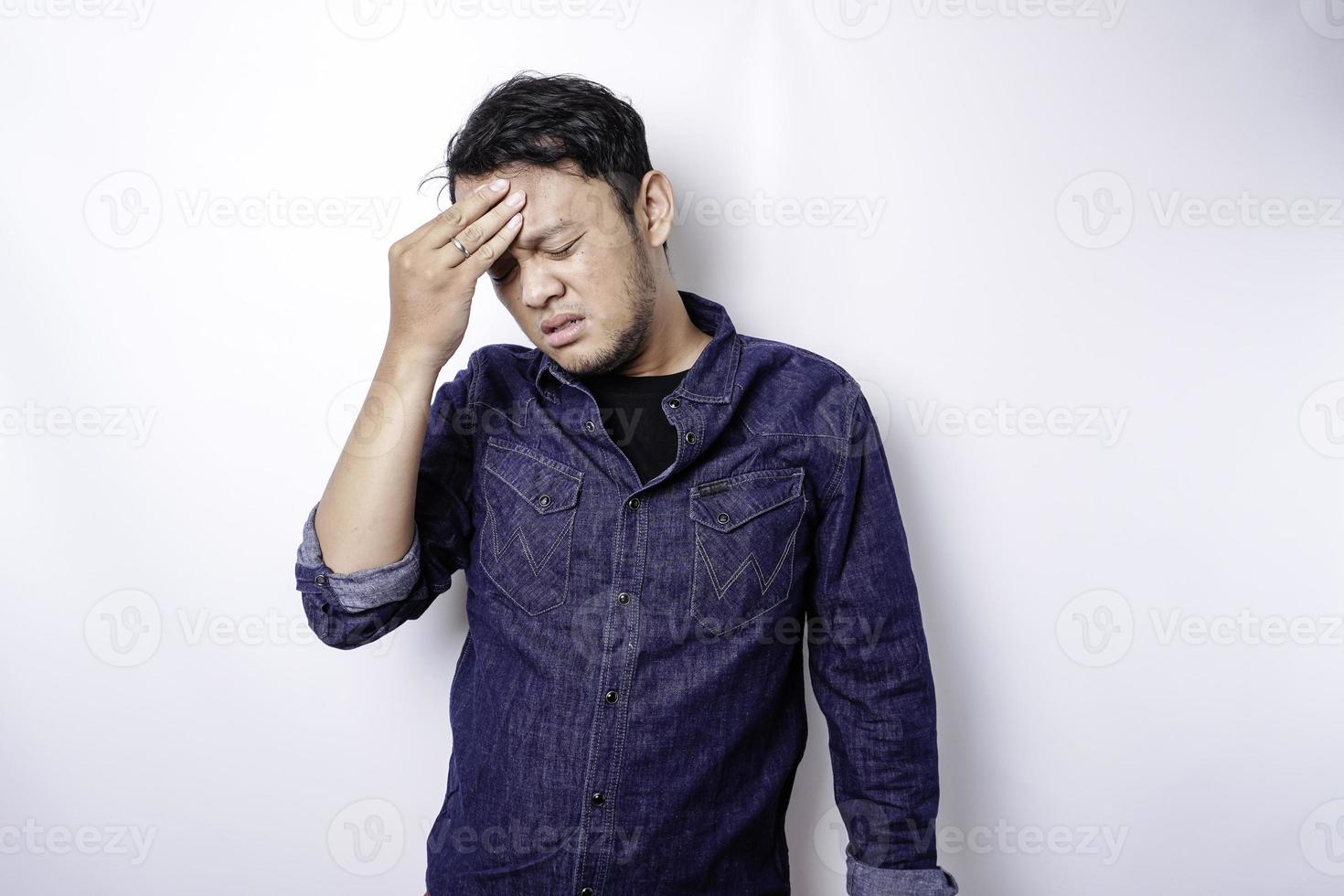 A portrait of an Asian man wearing a blue shirt isolated by white background looks depressed photo