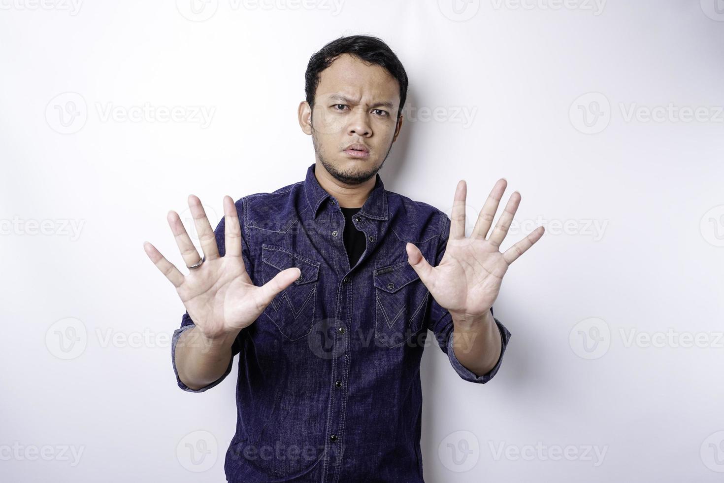 Handsome Asian man wearing blue shirt with hand gesture pose of stop or prohibition with copy space photo