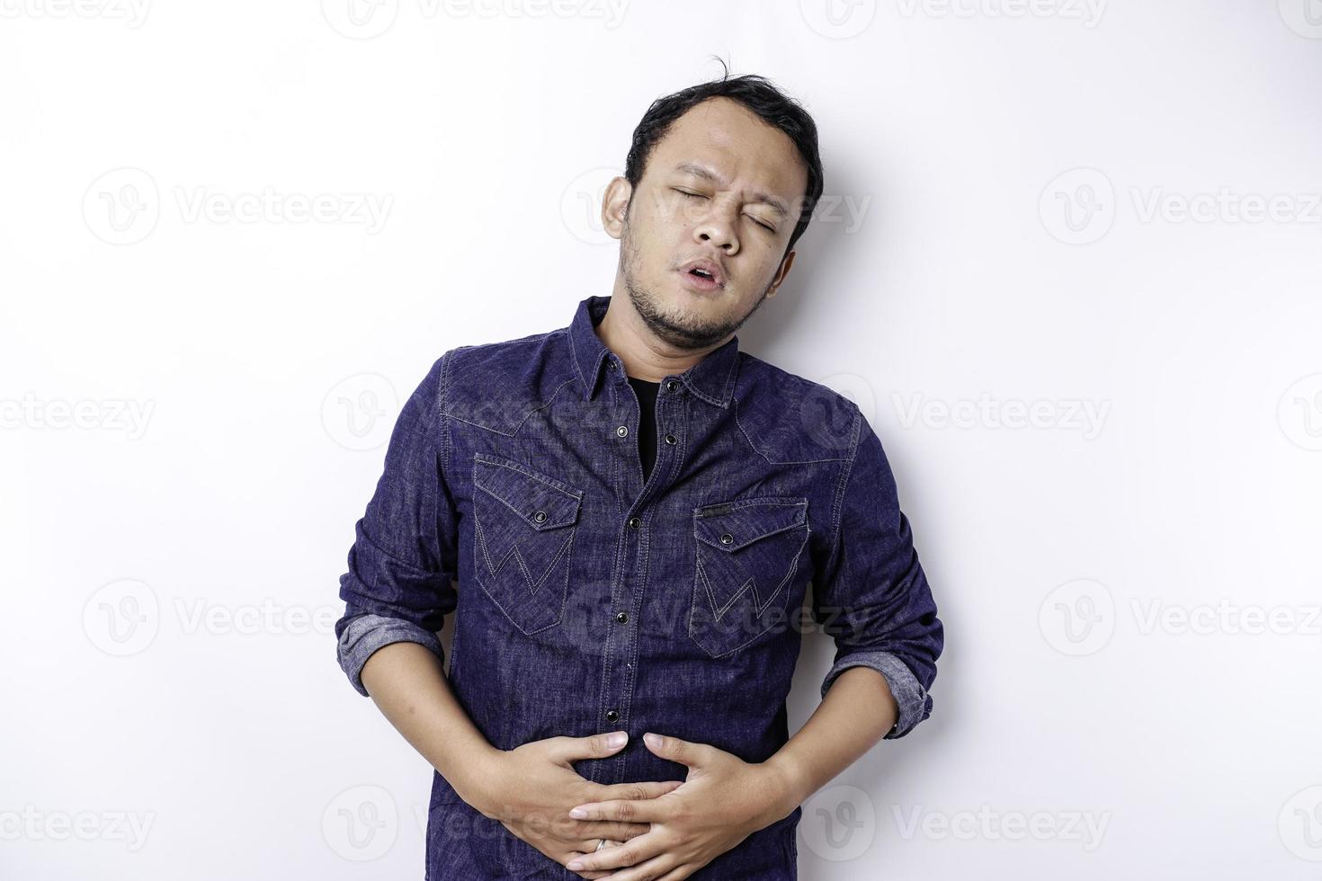 Photo of young unwell sick ill man hold hand on stomach suffers pain isolated on white background