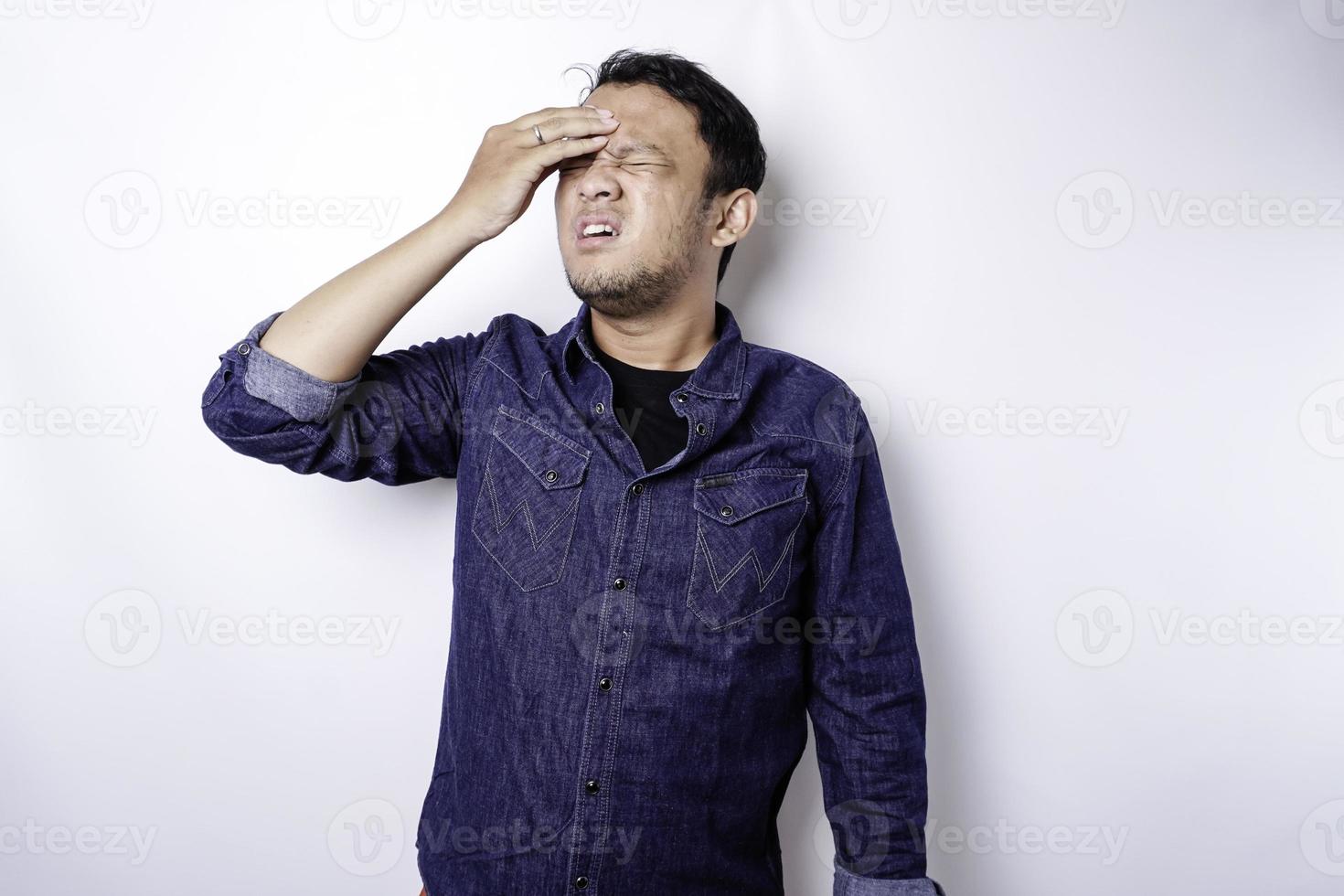 A portrait of an Asian man wearing a blue shirt isolated by white background looks depressed photo