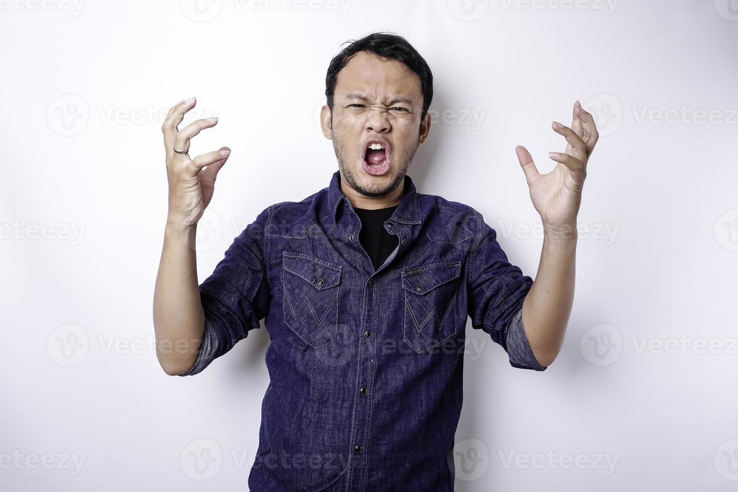 The angry and mad face of Asian man in blue shirt isolated white background. photo