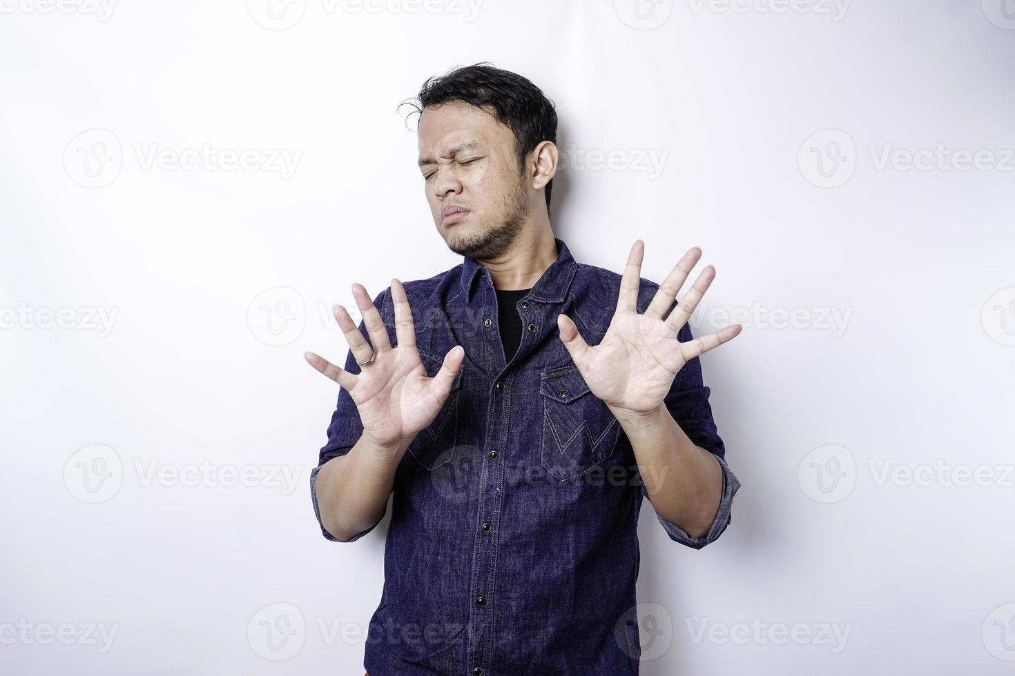 hombre asiático guapo con camisa azul con gesto de mano pose de parada o prohibición con espacio de copia foto