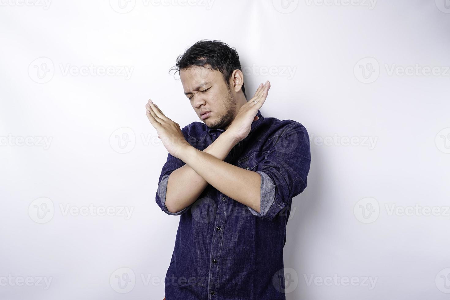 apuesto hombre asiático con camisa azul con gesto de la mano plantea rechazo o prohibición con espacio de copia foto