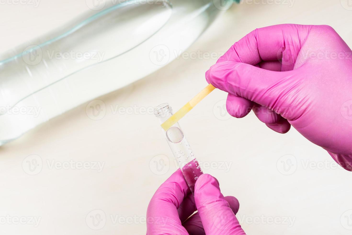 hand holds neutral litmus paper on test tube photo