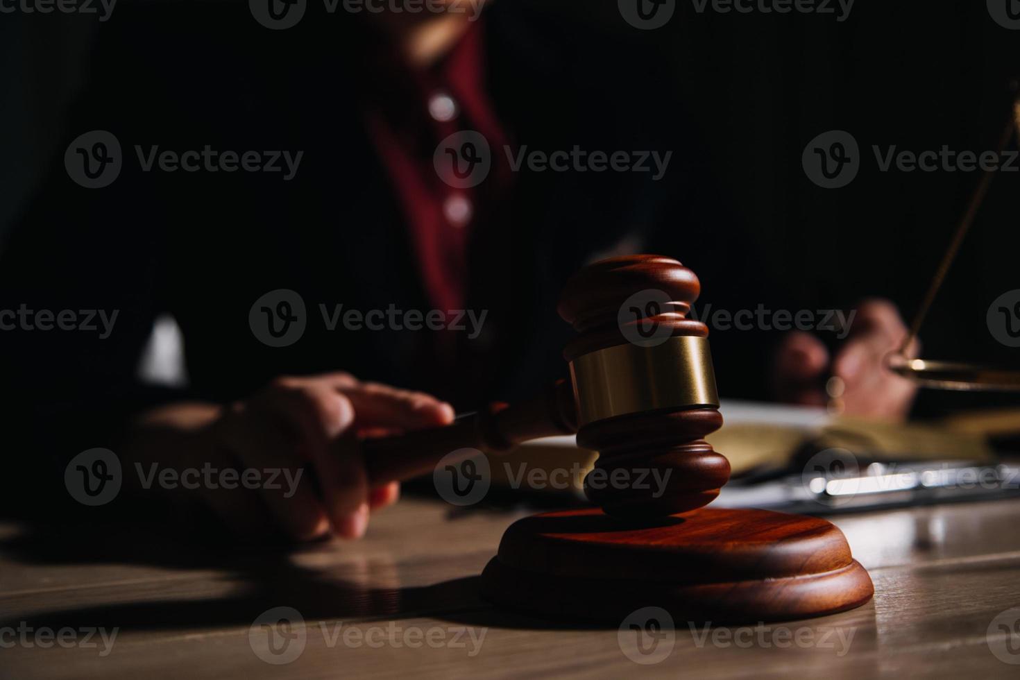 concepto de justicia y derecho. juez masculino en una sala de audiencias con el mazo, trabajando con computadora y teclado de acoplamiento, anteojos, en la mesa a la luz de la mañana foto