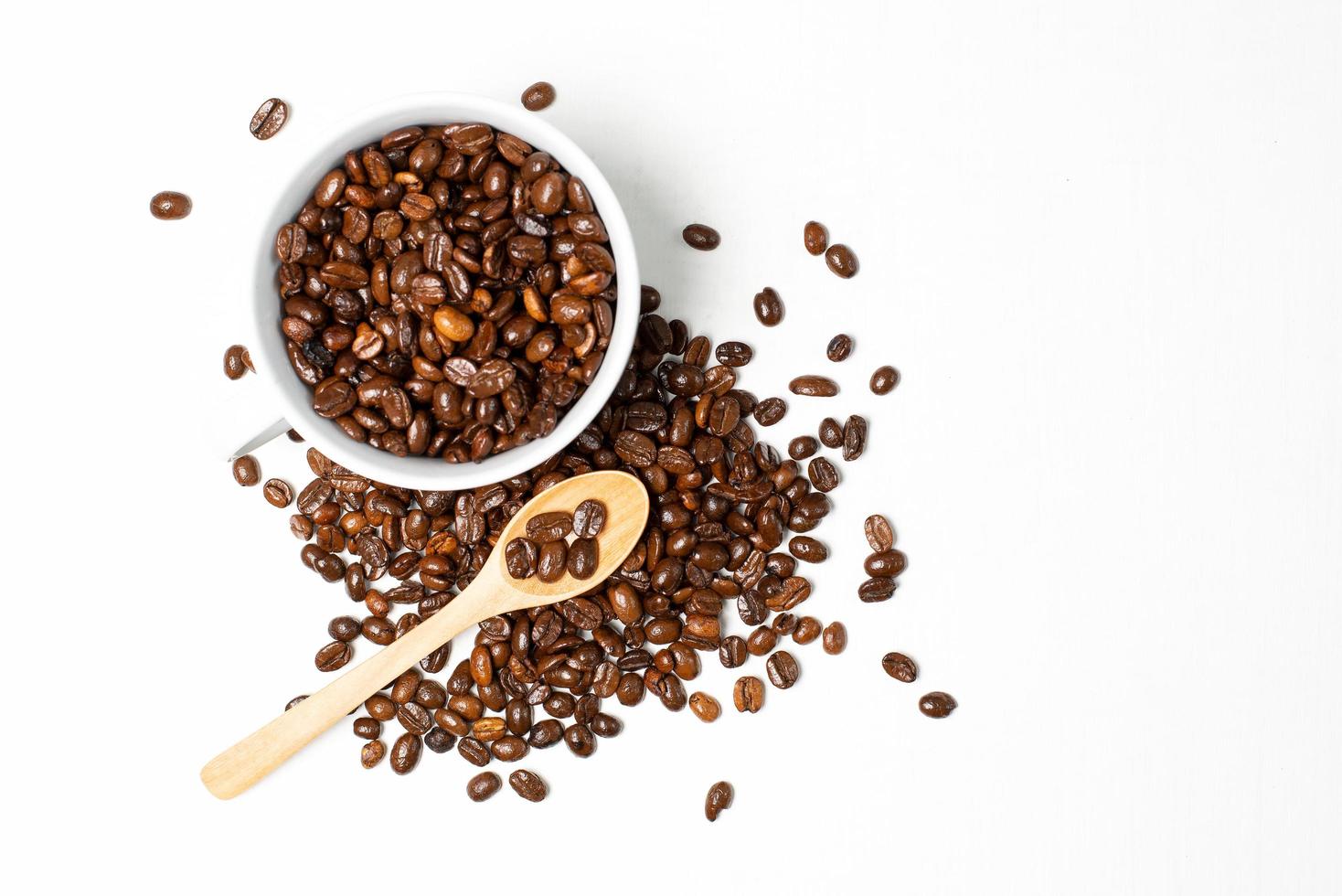 A cup of coffee and roasted coffee beans on white wood background photo
