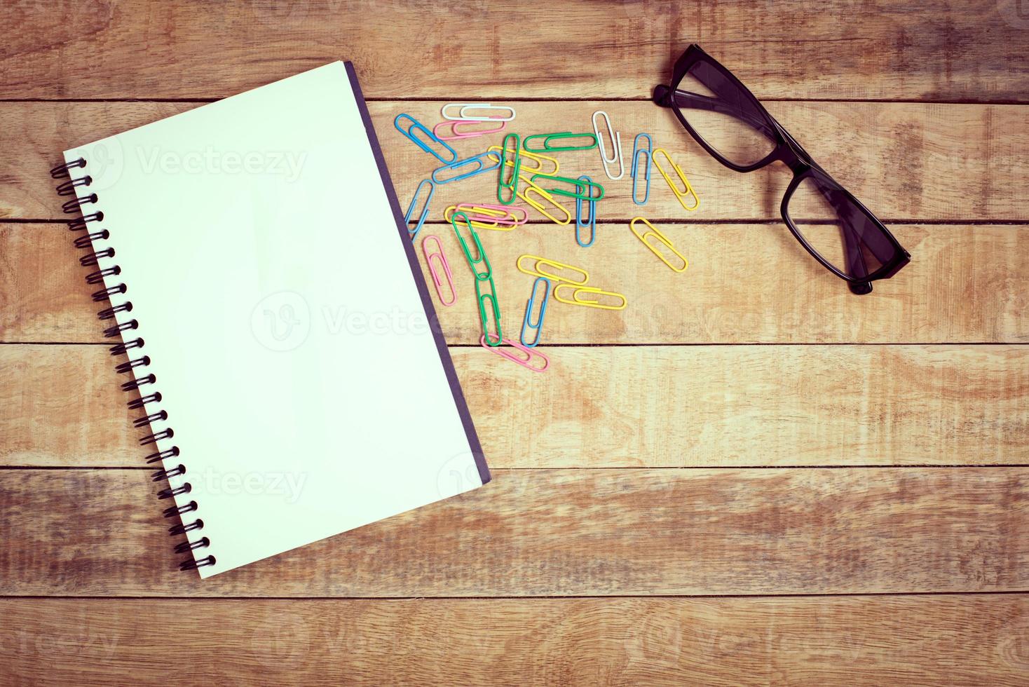 Blank notebook with pen and glasses on wood background photo