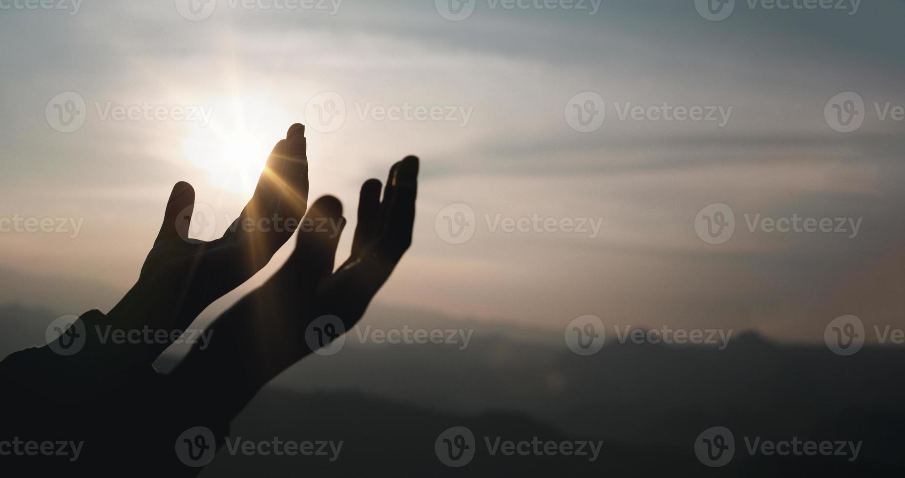 Banner of Faith christianity with christian worship concept. Spiritual prayer hands over sun shine with blurred beautiful sunset background. Woman praying to god with hopeful blessing against sunset. photo