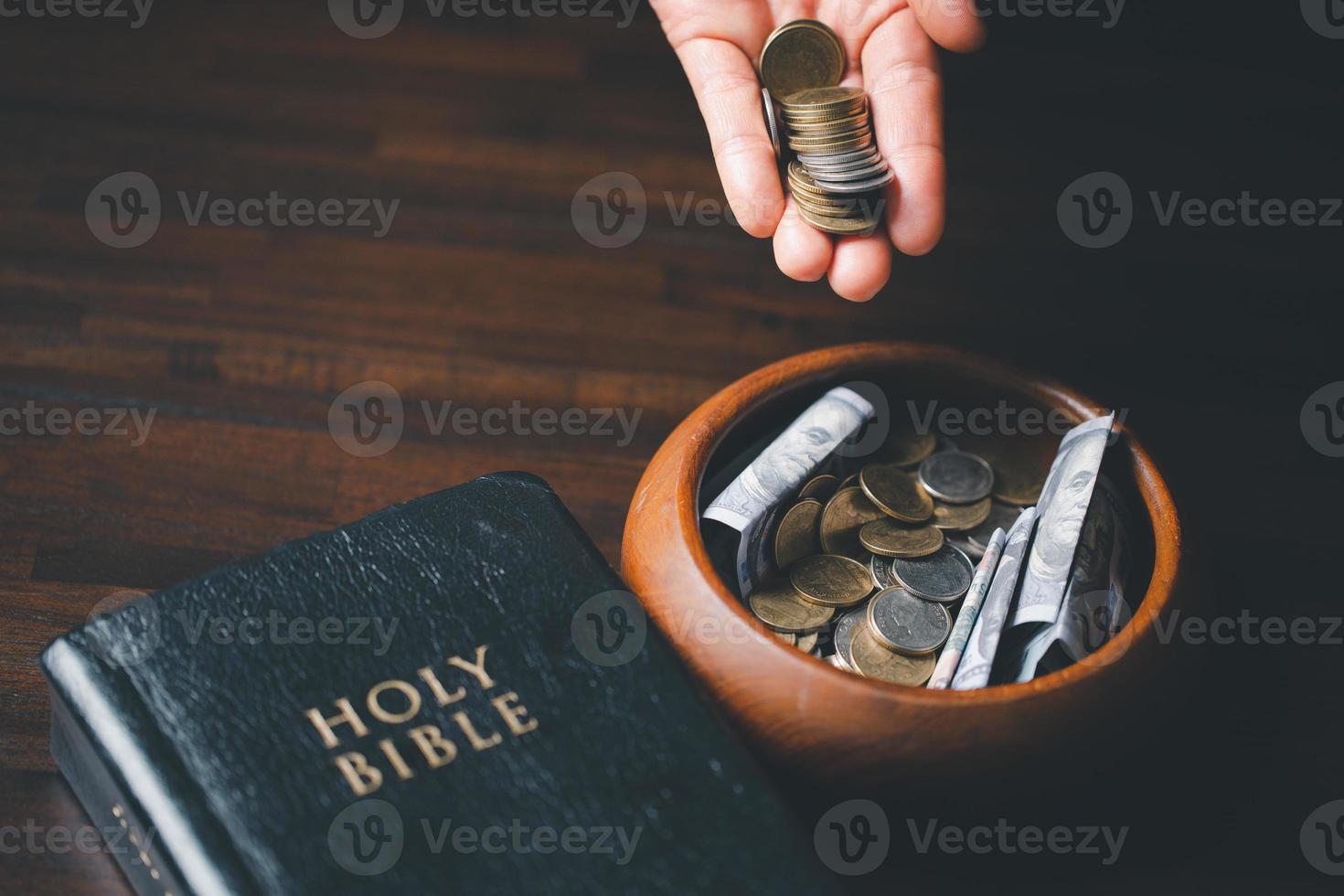 One tenth or tithe is basis on which Bible teaches us to give one tenth of first fruit to God. coins with Holy Bible. Biblical concept of Christian offering, generosity, and giving tithes in church. photo