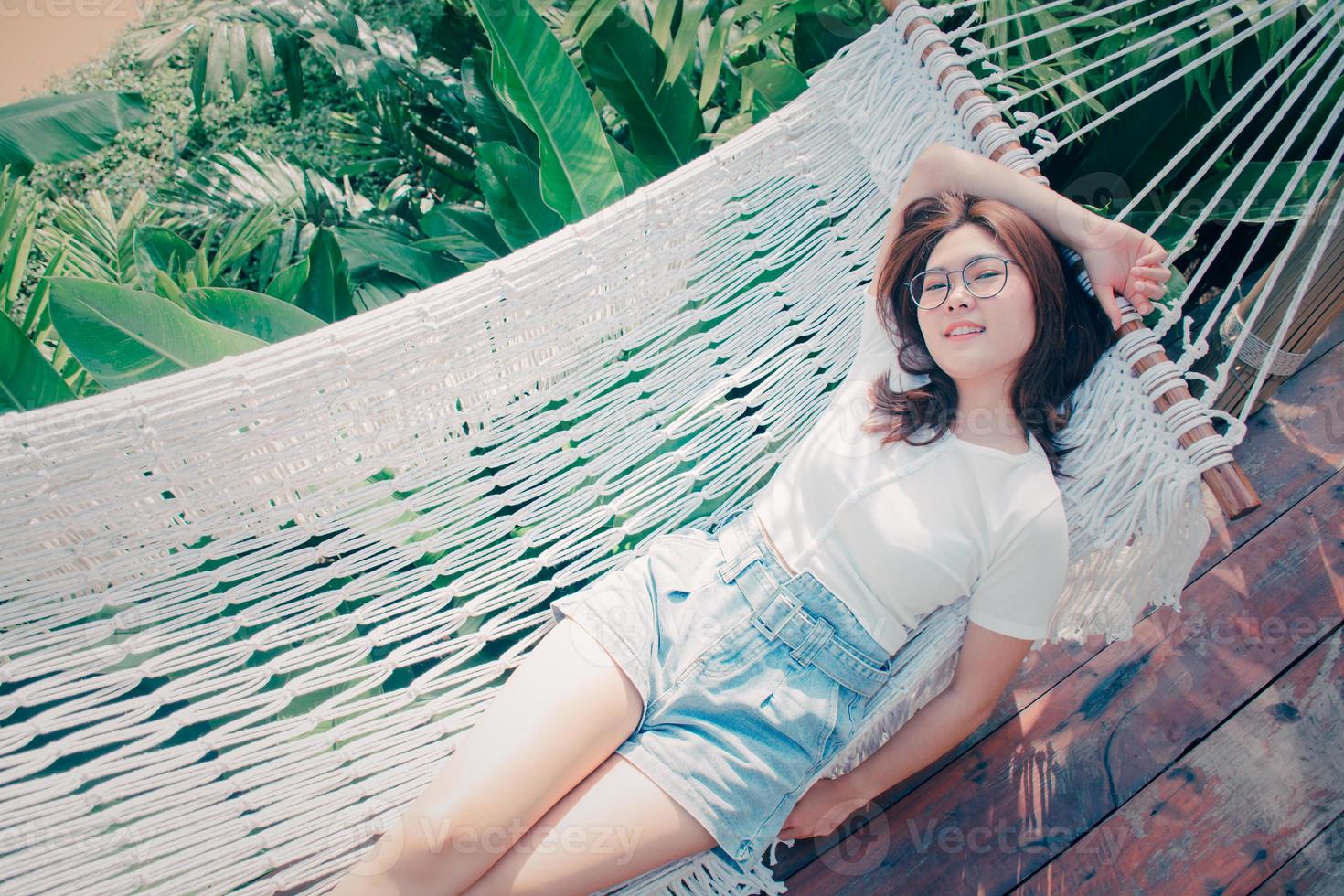 Pretty amazing cheerful young girl lying in a white hammock. She is smiling and looking at camera. relaxing day in the midst of nature by the canal. lifestyle, vacation life happiness concept. photo
