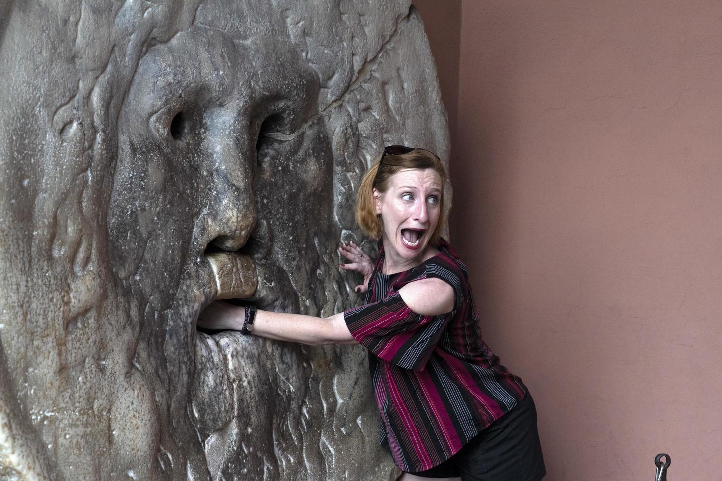 ROME, ITALY - JUNE 15 2019 - Tourist testing the mouth of truth mask photo