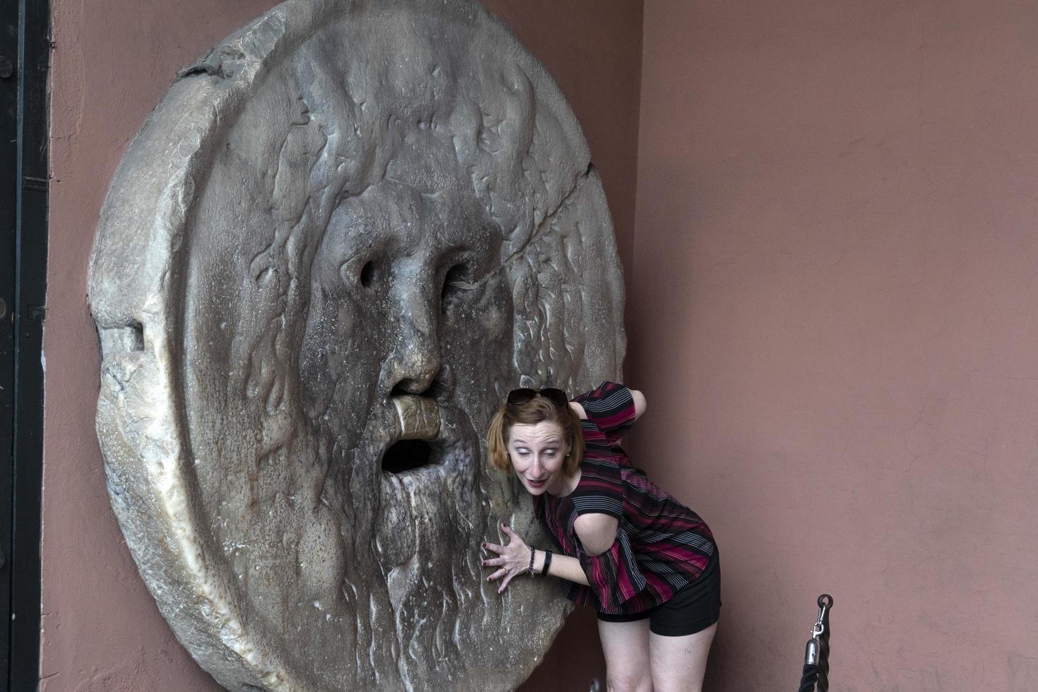 ROME, ITALY - JUNE 15 2019 - Tourist testing the mouth of truth mask photo